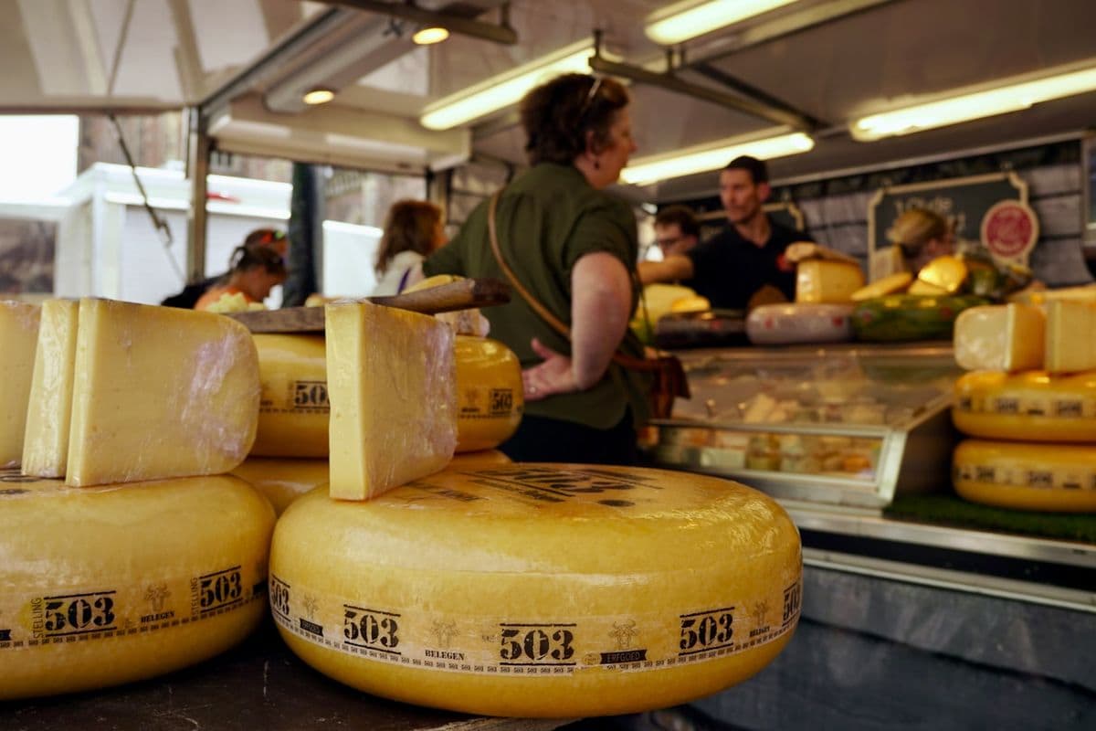 Cheese stall at a market with a shopkeeper behind it
