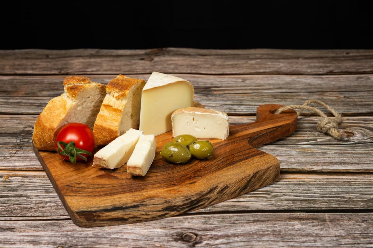 Cheese, bread, olives and tomato on a wooden board